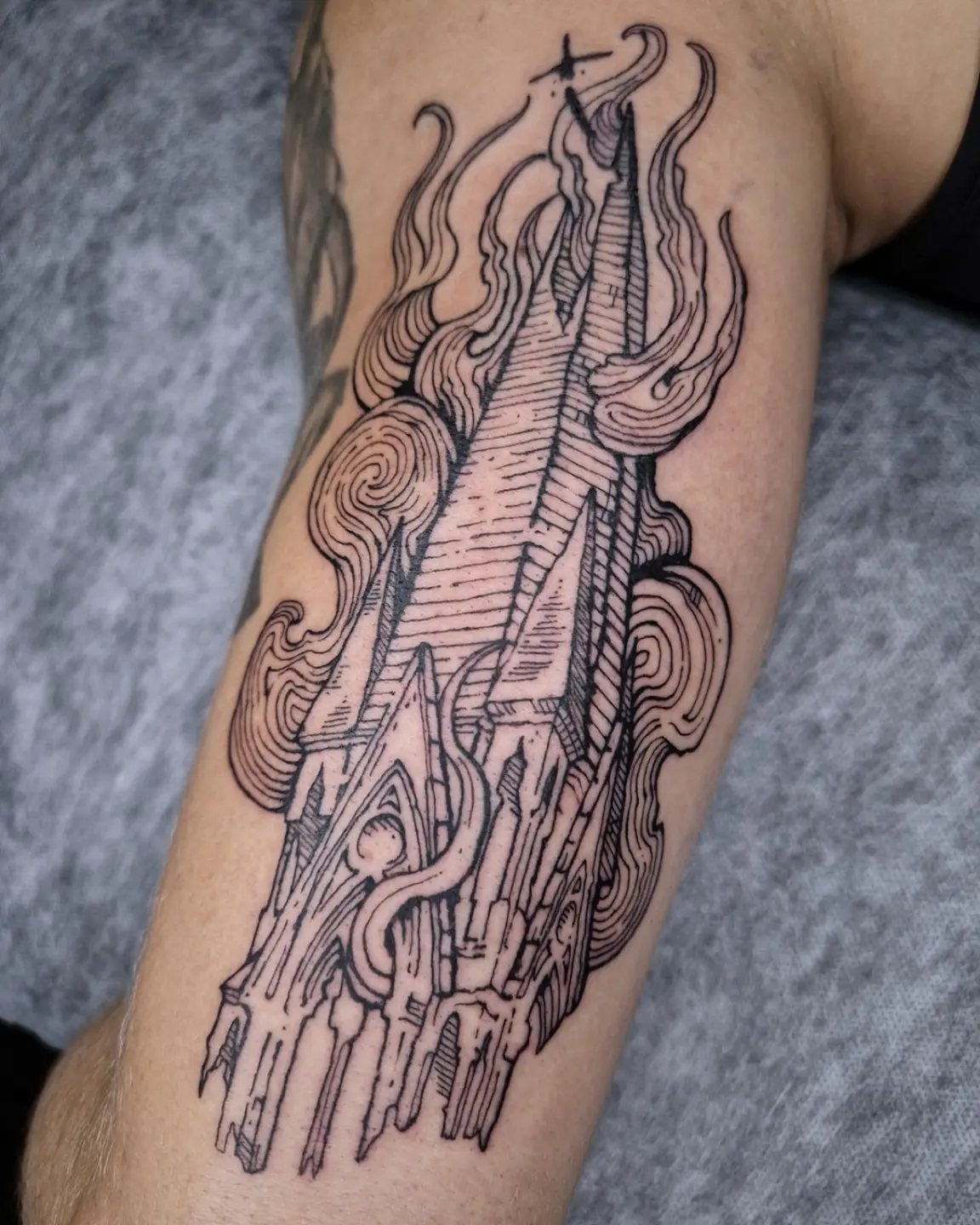 6 Burning Church Tattoo Ideas for Dark, Dramatic Ink 1 A black ink tattoo of a gothic church steeple engulfed in swirling flames on an arm.
