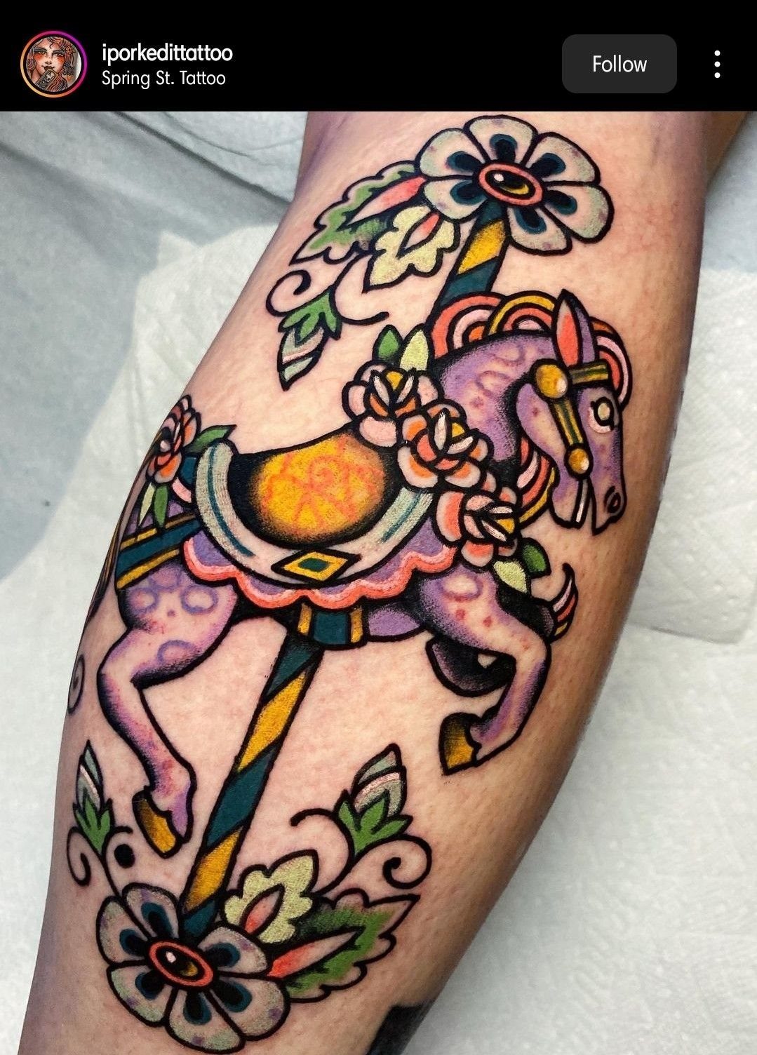 A colorful tattoo of a purple carousel horse adorned with pink flowers on a person's arm.