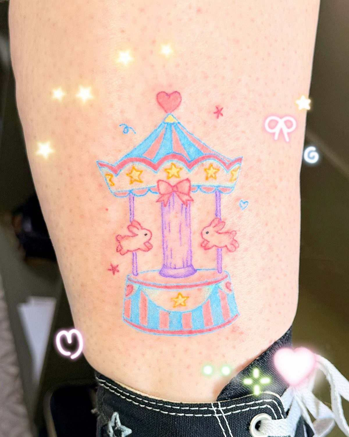 A colorful carousel tattoo with pink animal figures on a person's leg.