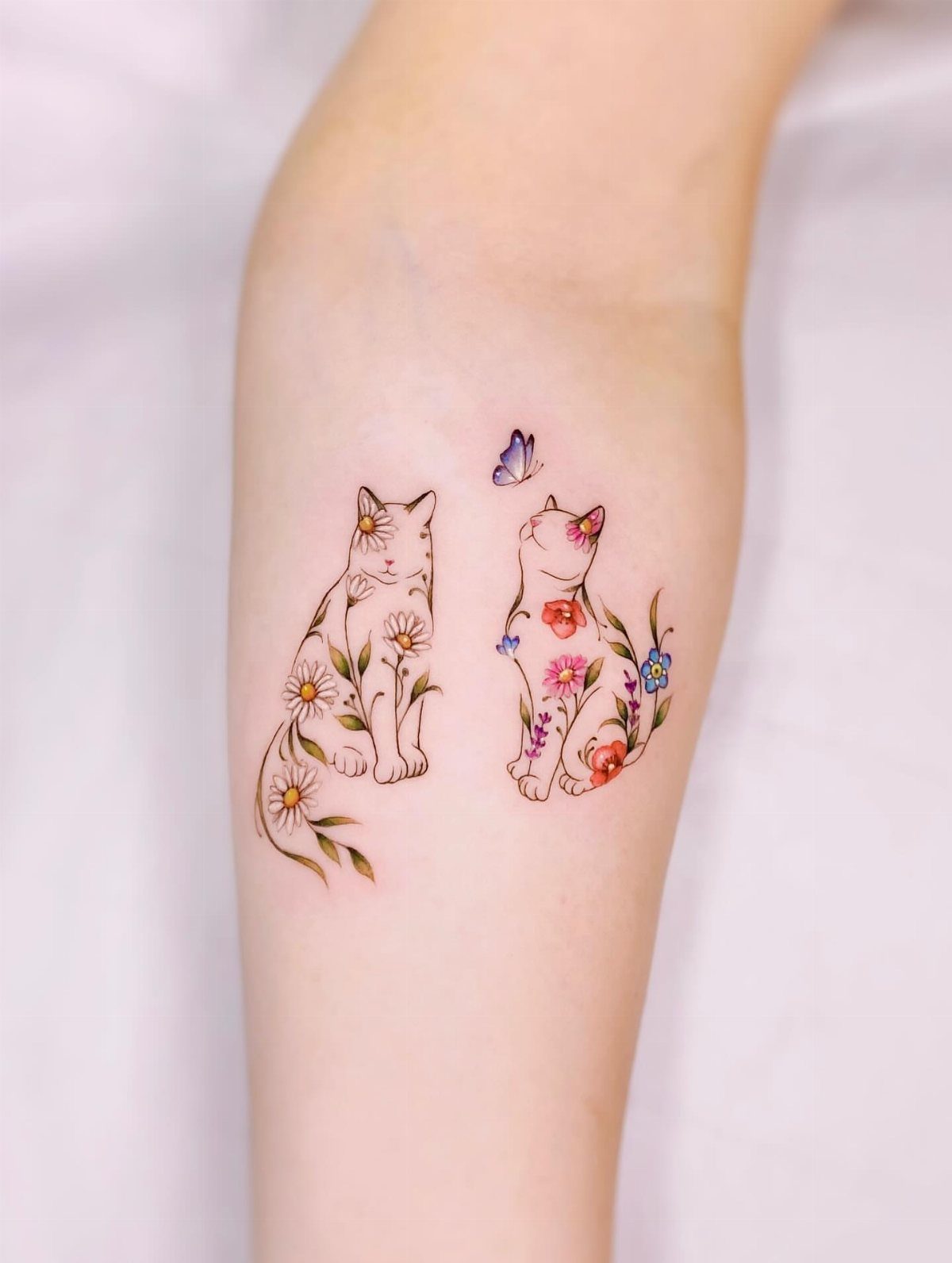 Cat Tattoo with Pattern: 8 Bold Design Ideas to Consider 1 Two small cat tattoos featuring colorful floral patterns and a butterfly on a person's arm.