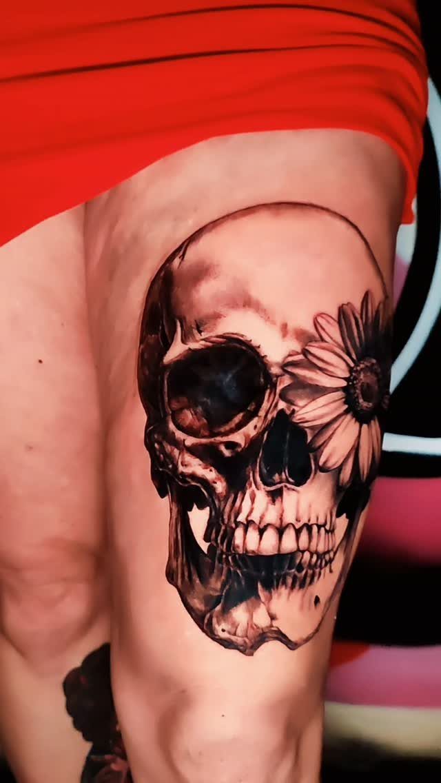 Cover Up Tattoo Pattern: 9 Ways to Hide Old Ink or Scars 5 A large black and grey skull tattoo with a daisy flower on a person's thigh.