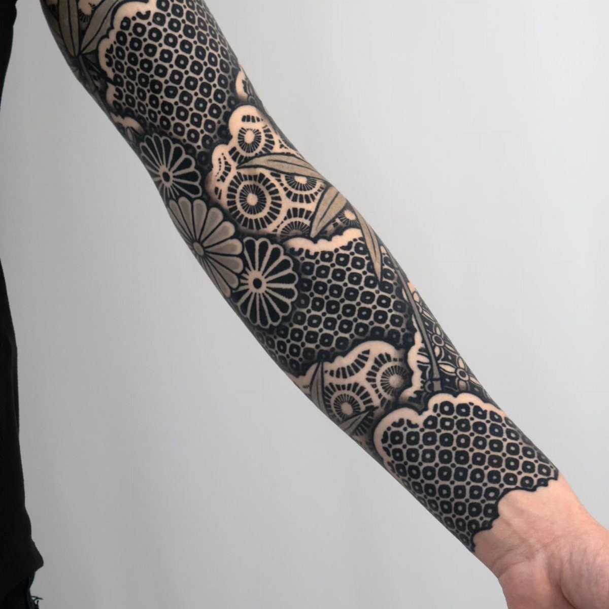 Cover Up Tattoo Pattern: 9 Ways to Hide Old Ink or Scars 8 A person's arm featuring a detailed black and grey floral and geometric sleeve tattoo.