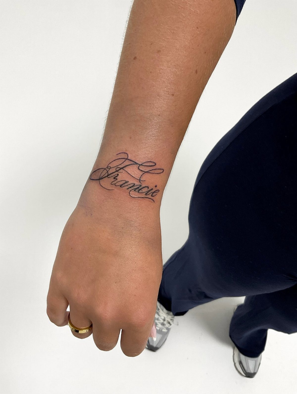 A person's wrist displaying a black cursive script tattoo that reads Francie.