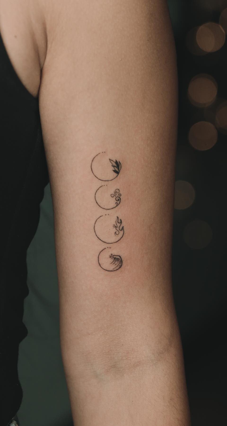 9 Earth Element Tattoo Ideas for Symbols, Scenery and Spirit 4 Four small minimalist circular tattoos arranged vertically on a person's forearm.