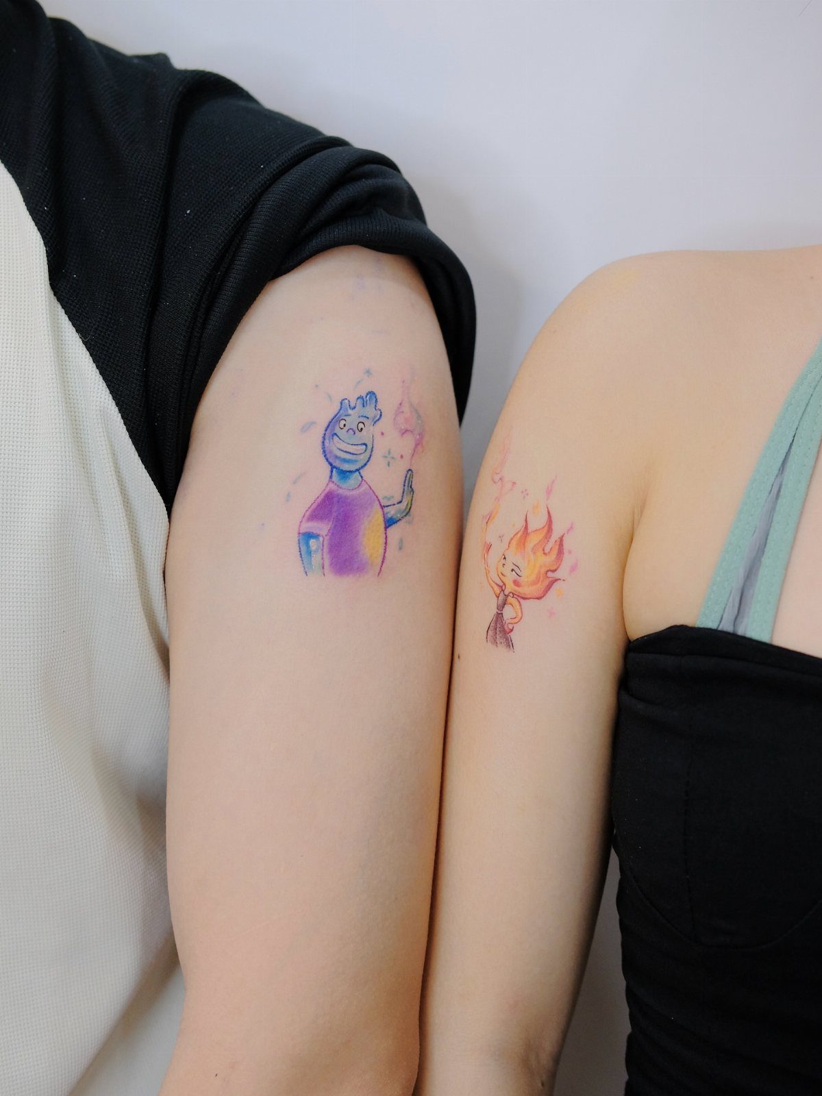 11 Elemental Tattoo Ideas for Your Next Ink 11 Two arms side-by-side displaying small, colorful watercolor elemental character tattoos.