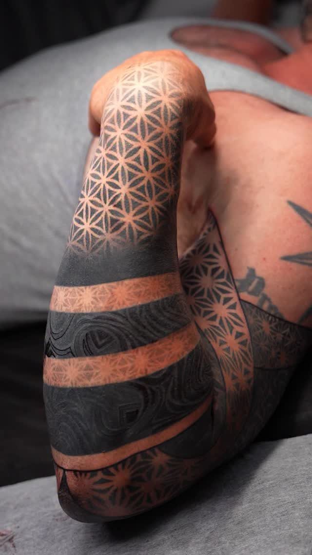 8 Full Arm Tattoo Ideas for Men and Women 1 A person's arm covered in detailed black and grey geometric tattoos and thick patterned bands.
