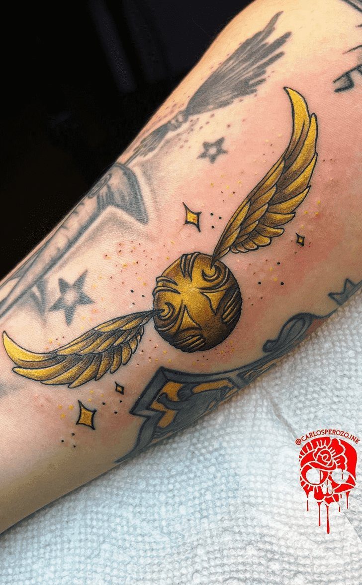 Golden Snitch Tattoo: 7 Styles From Minimalist to Metallic Ink 5 A golden snitch tattoo with small black stars on a person's arm.