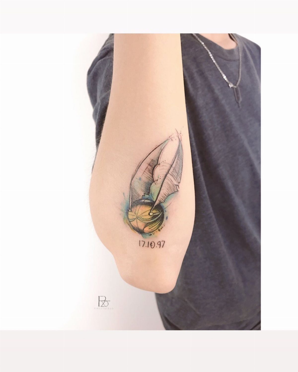 Golden Snitch Tattoo: 7 Styles From Minimalist to Metallic Ink 4 A golden snitch tattoo with watercolor accents and numbers on a person's arm.