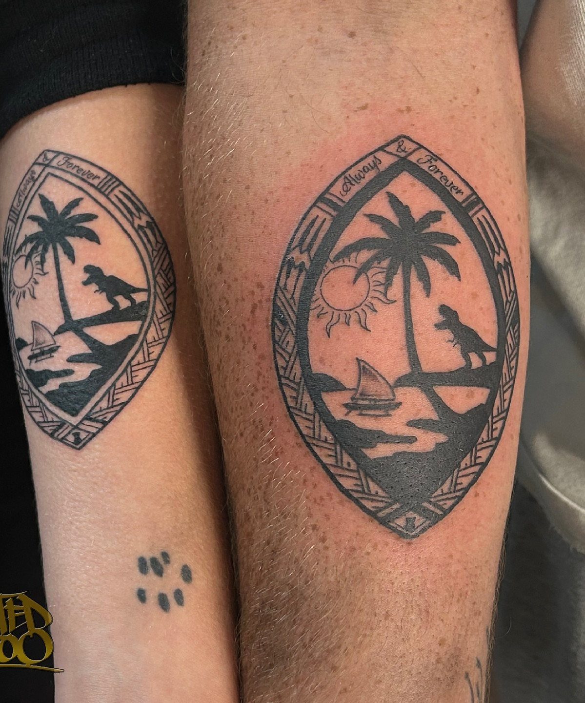 Two black ink tattoos on arms featuring a tropical scene inside a geometric diamond frame.