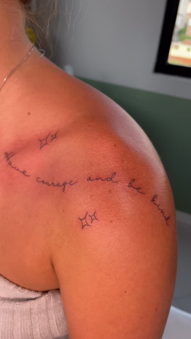 Have Courage and Be Kind Tattoo: 6 Designs Worth Committing To 4 A fine-line black ink tattoo on a person's shoulder reading have courage and be kind.
