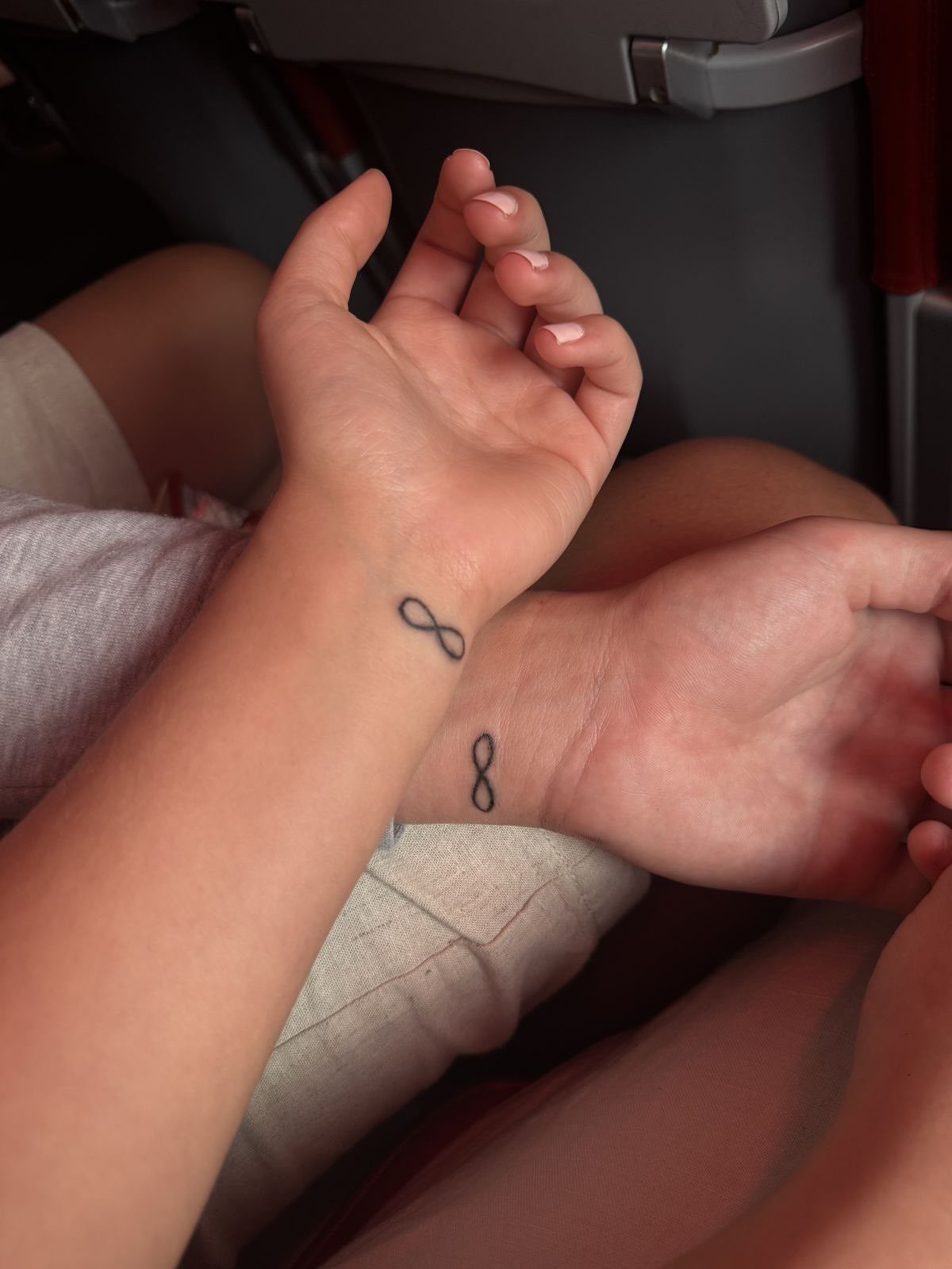 9 Minimalist Couple Tattoo Ideas Unique and Subtle for Lasting Ink 5 Two wrists held together showing small black minimalist infinity symbol tattoos.