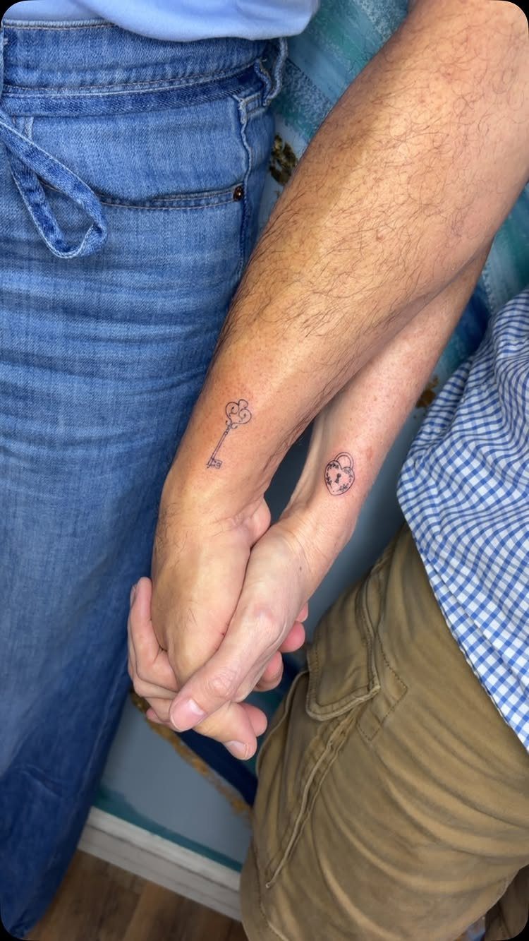 9 Minimalist Couple Tattoo Ideas Unique and Subtle for Lasting Ink 4 Two people holding hands with matching key and padlock tattoos on their wrists.