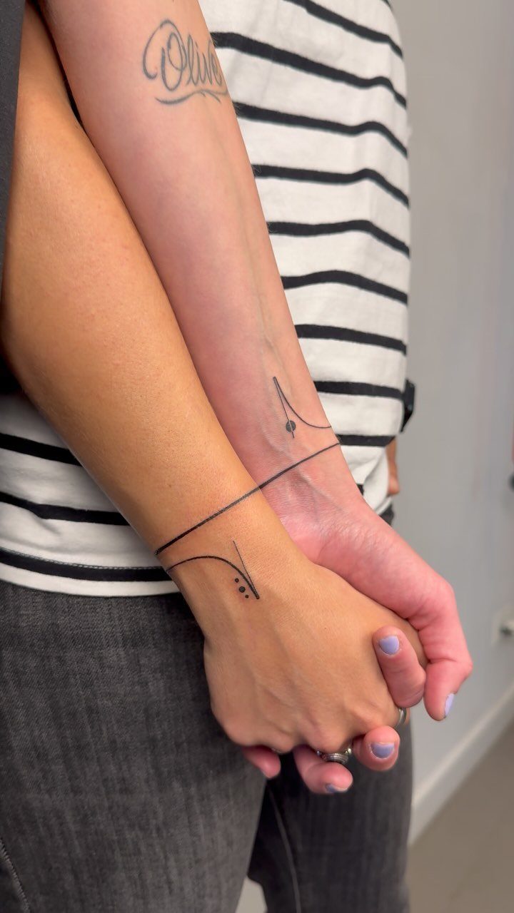 9 Minimalist Couple Tattoo Ideas Unique and Subtle for Lasting Ink 8 Two people holding hands with matching minimalist line tattoos on their wrists.