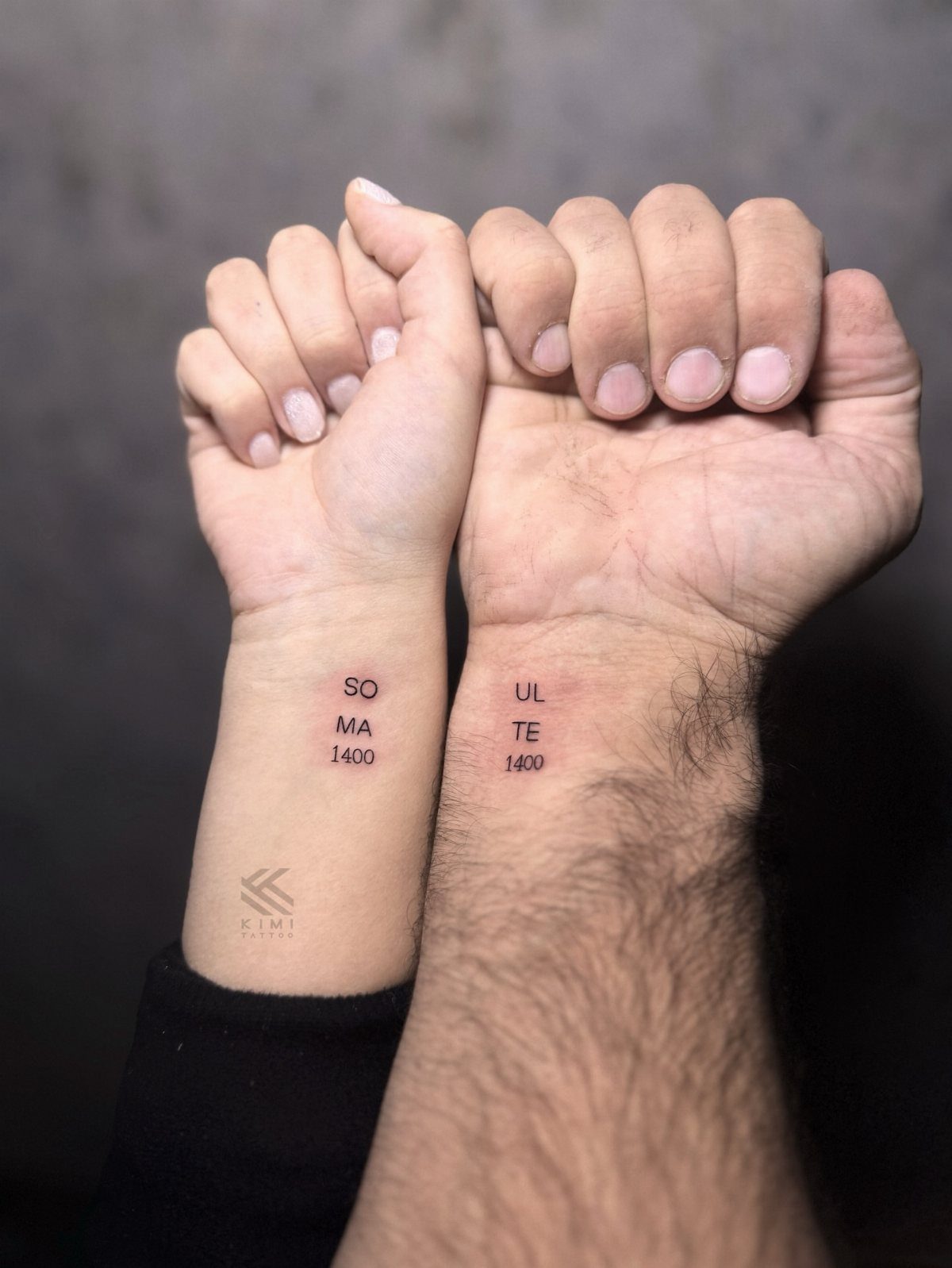 9 Minimalist Couple Tattoo Ideas Unique and Subtle for Lasting Ink 2 Two wrists held together showing small black ink tattoos that form the word soulmate.