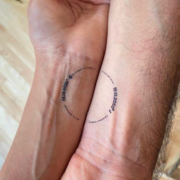 9 Minimalist Couple Tattoo Ideas Unique and Subtle for Lasting Ink 6 Two wrists held together showing matching circular dotted tattoos with the date 19.12.2020.