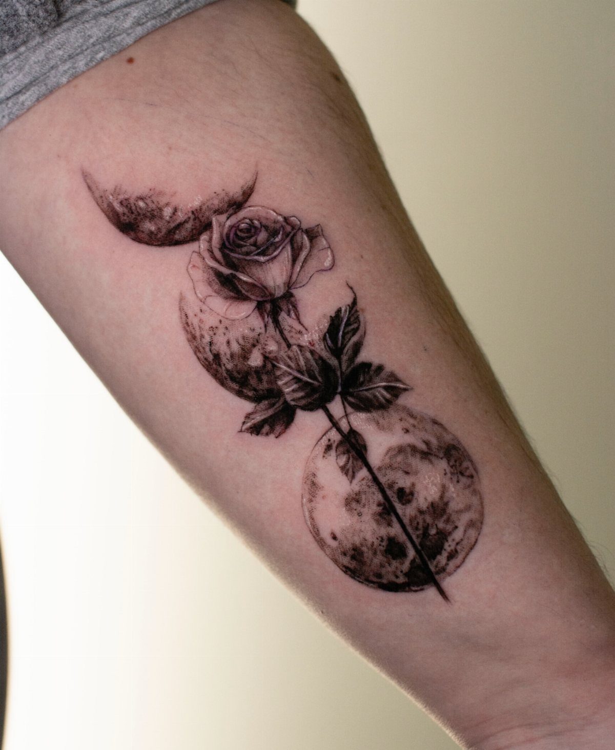 Moon Phases Tattoo Designs for Women: 8 Ideas to Consider 8 A black and grey tattoo of a rose and moon phases on a person's arm.