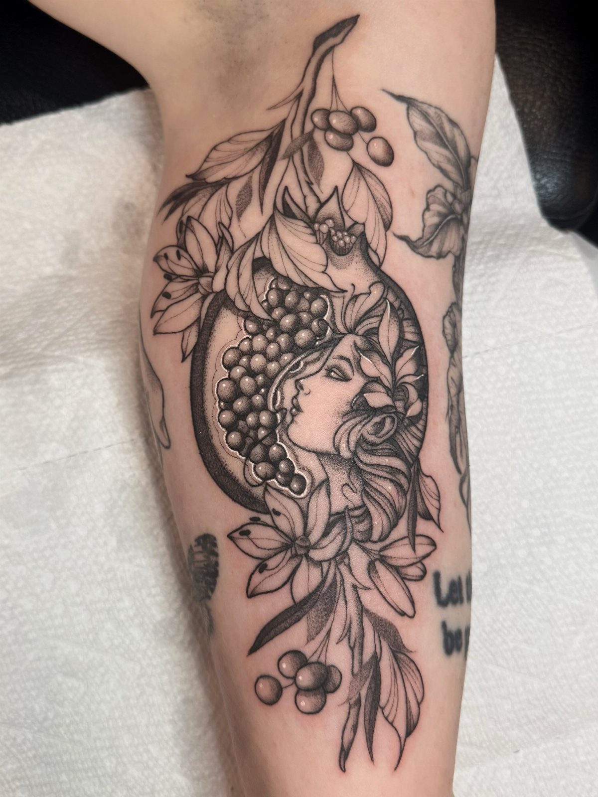 Pomegranate Tattoo Ideas: 11 Designs from Myth to Botanical 1 Black and grey tattoo on a leg depicting a pomegranate with a woman's face inside.