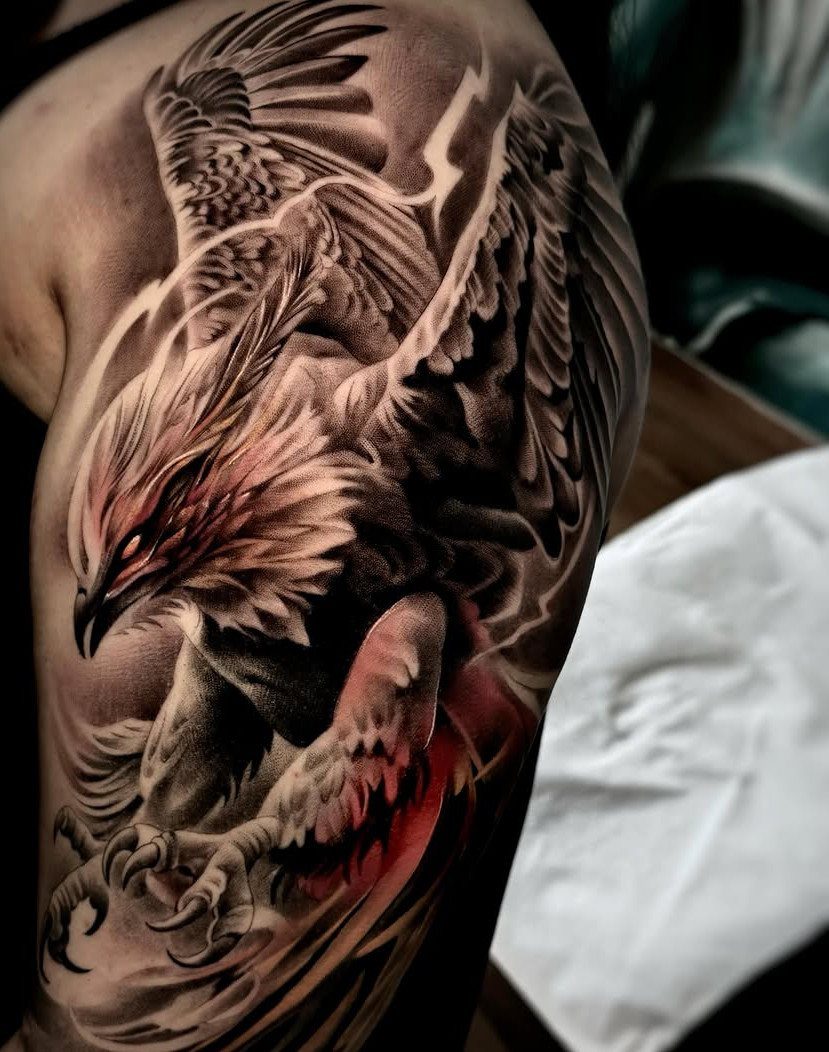 A detailed phoenix tattoo with red highlights on a person's shoulder and upper arm.