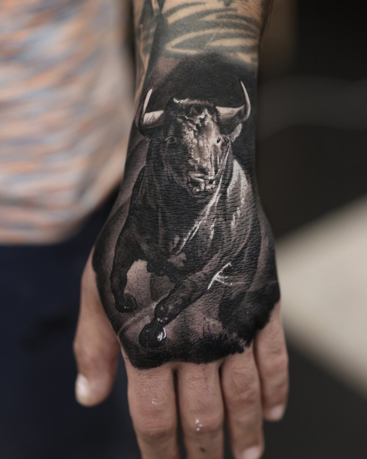 16 Realistic Bull Tattoo Ideas for Strength and Style 14 A detailed black and grey bull tattoo covering the entire back of a person's hand.