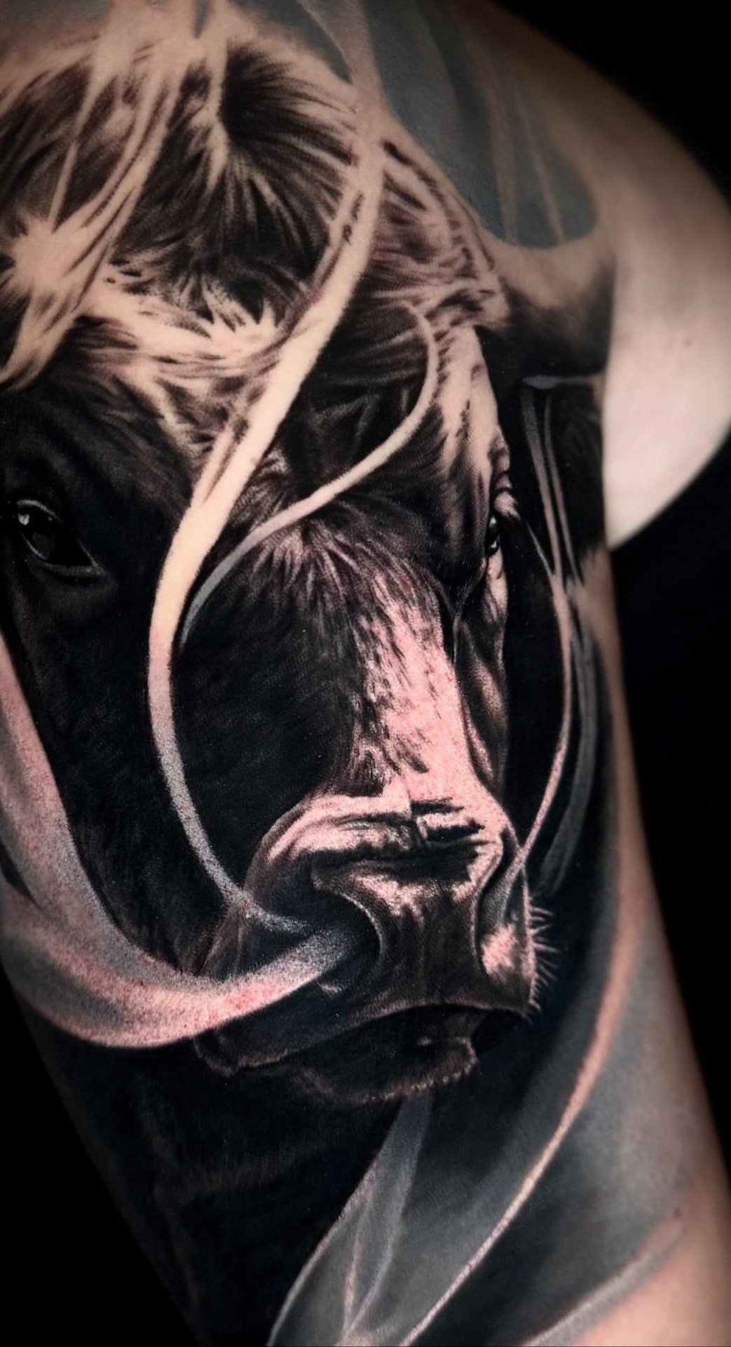 16 Realistic Bull Tattoo Ideas for Strength and Style 15 A realistic black and grey bull tattoo with flowing white smoke patterns on skin.