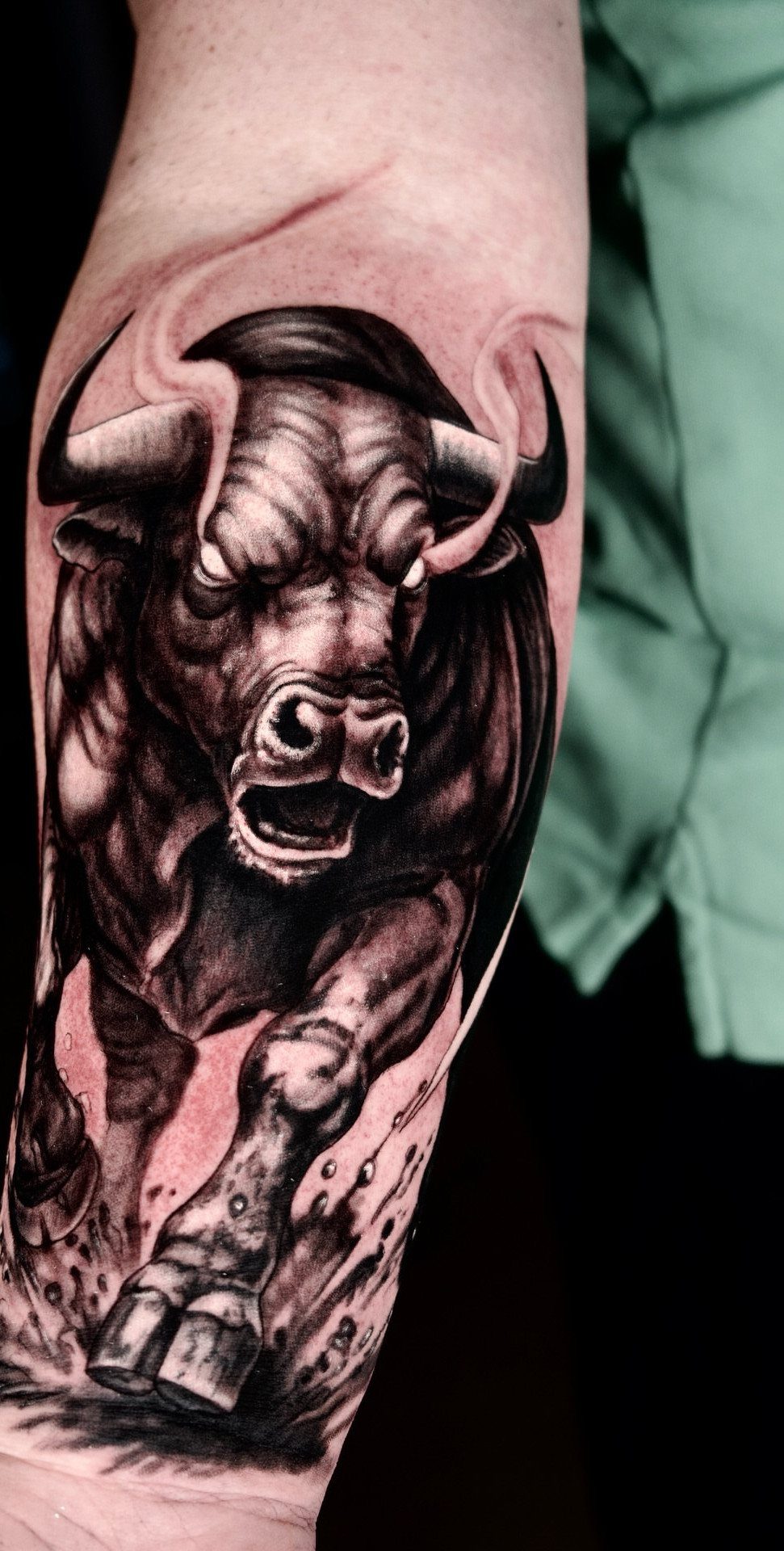 16 Realistic Bull Tattoo Ideas for Strength and Style 1 A detailed black and grey realistic bull tattoo on a person's forearm.