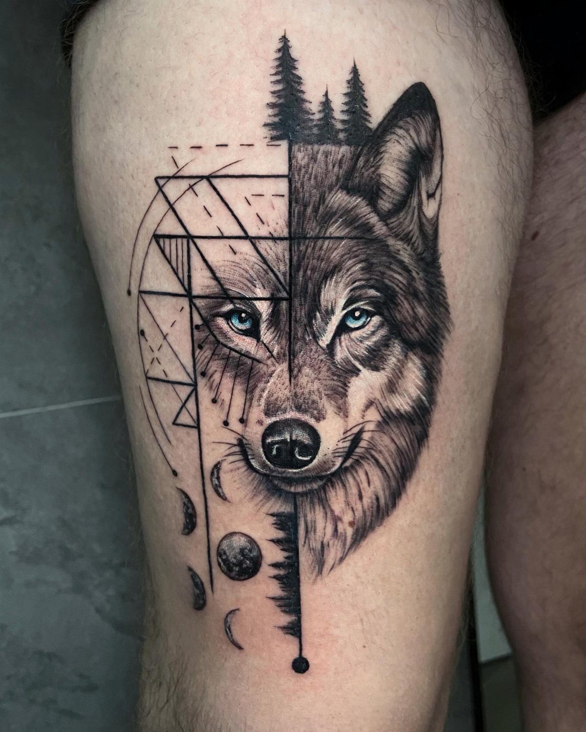 Running Wolf Tattoo: 7 Designs That Move 3 A detailed black and grey wolf tattoo featuring geometric patterns and forest elements on skin.
