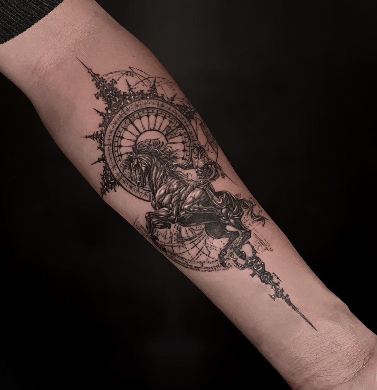 A detailed black and grey centaur archer tattoo on a person's forearm with celestial background elements.