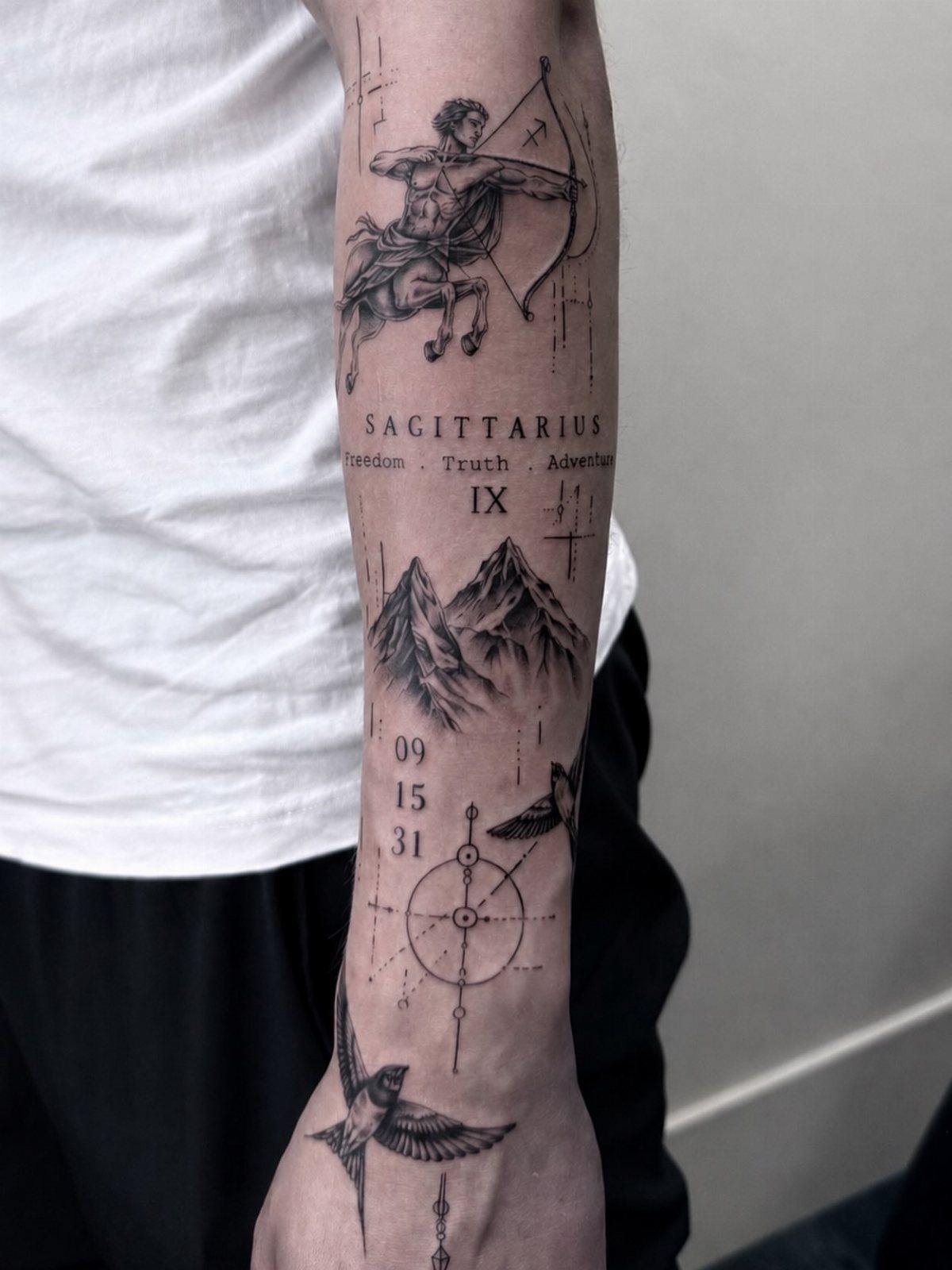 A detailed black ink forearm tattoo featuring a centaur archer, mountains, and a compass design.