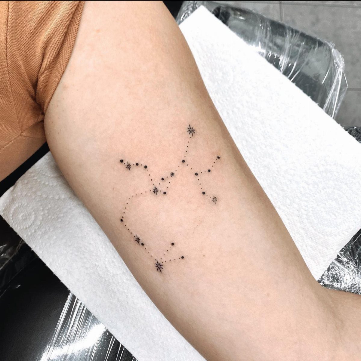 A minimalist Sagittarius constellation tattoo inked in black on a person's forearm.