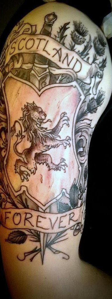 7 Scottish Lion Tattoo Ideas for Your Next Ink 1 A large arm tattoo depicting a lion rampant on a shield with thistles and banners.
