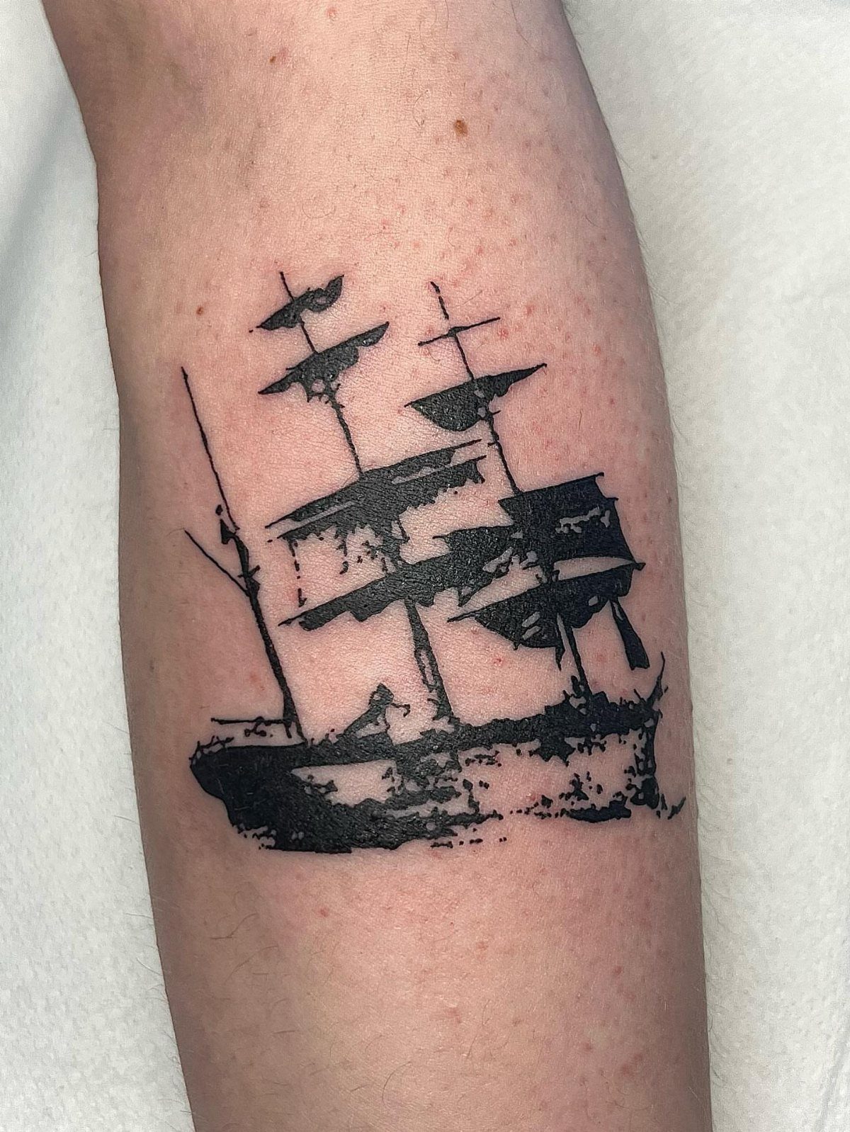 16 Ship Tattoo Ideas in Anchor, Viking, Pirate and Seascape Styles 6 A black ink minimalist sailing ship tattoo on a person's forearm.