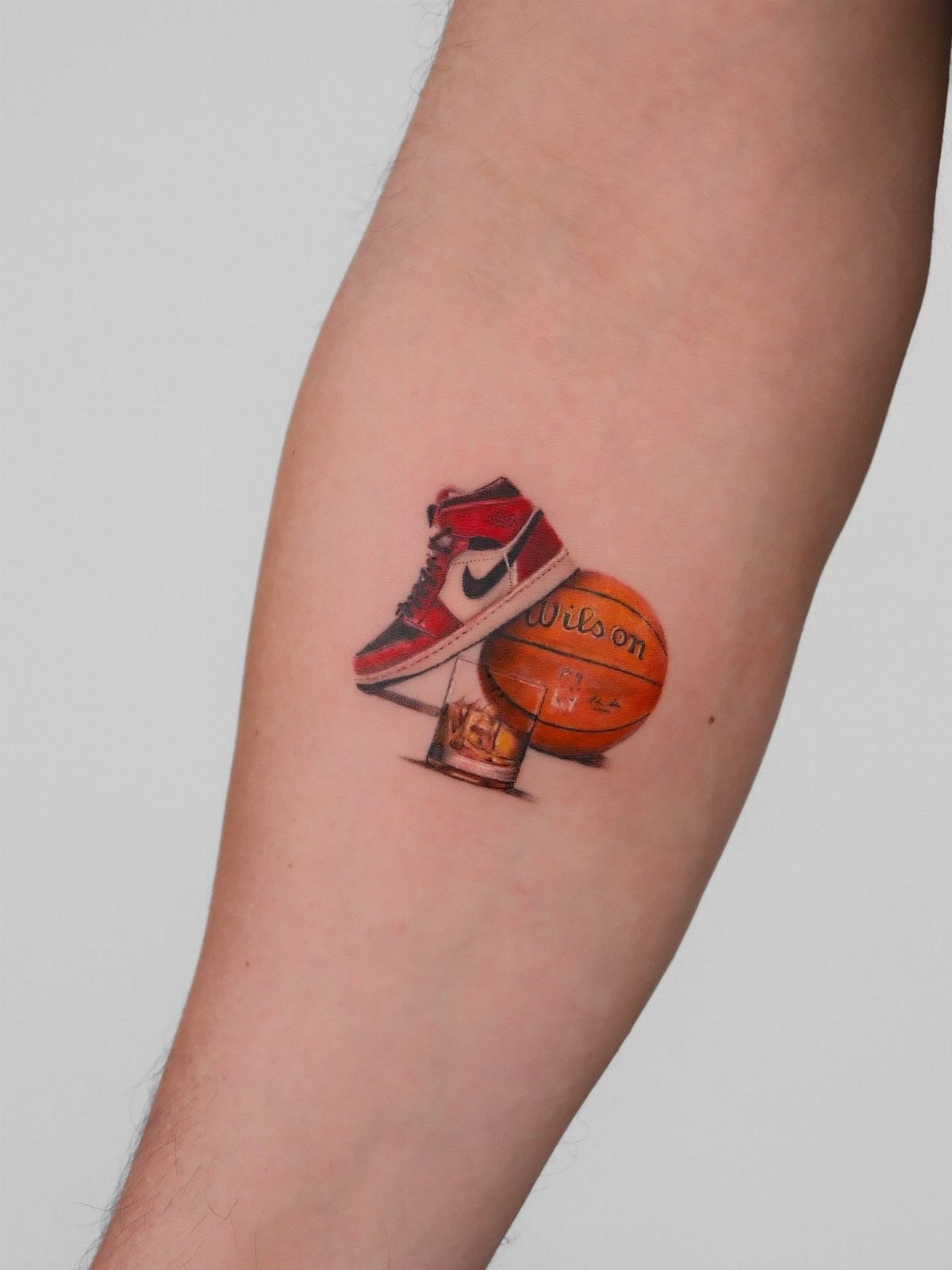 9 Sneaker Tattoo Ideas for Streetwear and Sport Ink 6 A small tattoo of a red high-top sneaker and an orange basketball on skin.