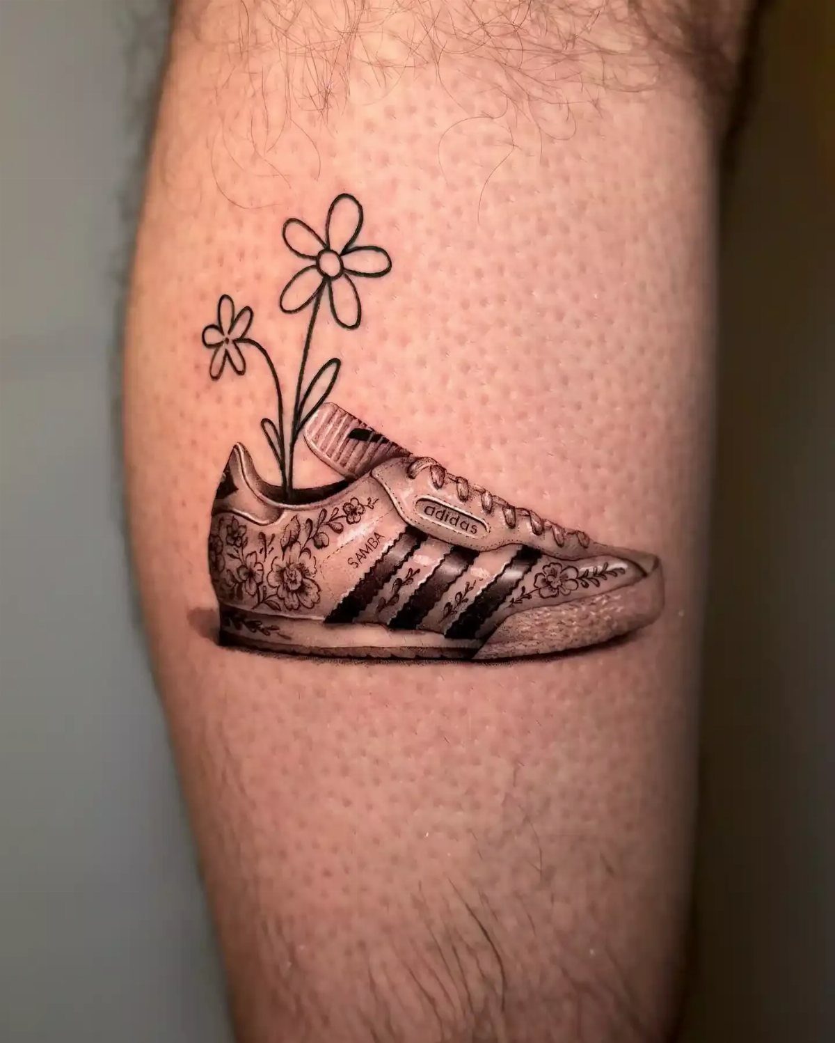 9 Sneaker Tattoo Ideas for Streetwear and Sport Ink 2 A tattoo of a floral patterned Adidas sneaker with flowers growing out of it on a leg.