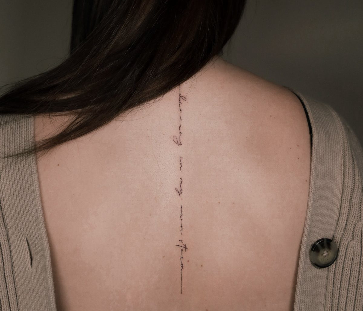Storm Tattoo: 8 Nature-Inspired Designs for Your Next Ink 8 Fine line script tattoo running vertically down a person's spine on their upper back.
