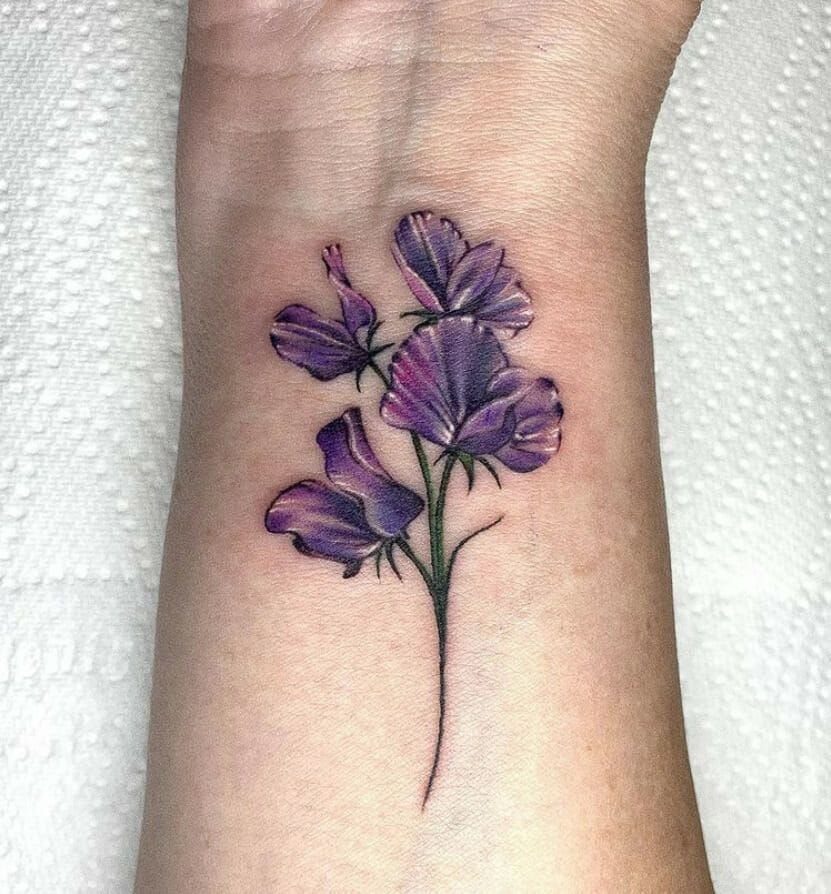 Sweet Pea Flower Tattoo: 7 Ideas for Placement and Style 5 Purple sweet pea flower tattoo with green stems on a person's wrist.