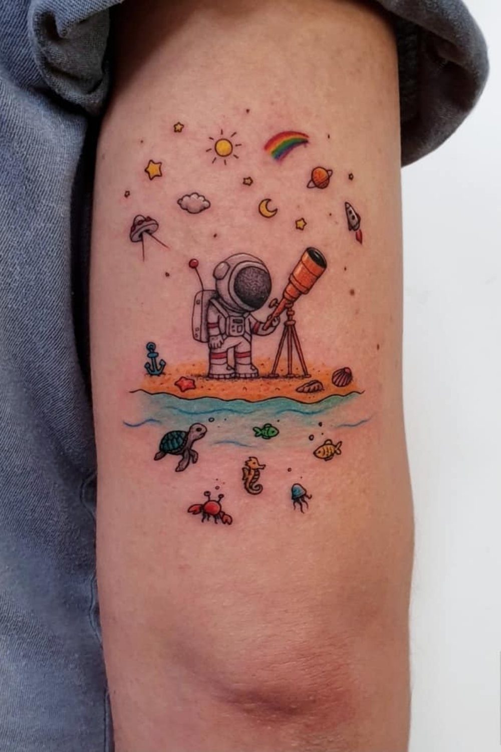 7 Telescope Tattoo Ideas for Every Space and Style 4 Astronaut using a telescope on a beach with sea creatures and celestial objects tattooed on an arm.