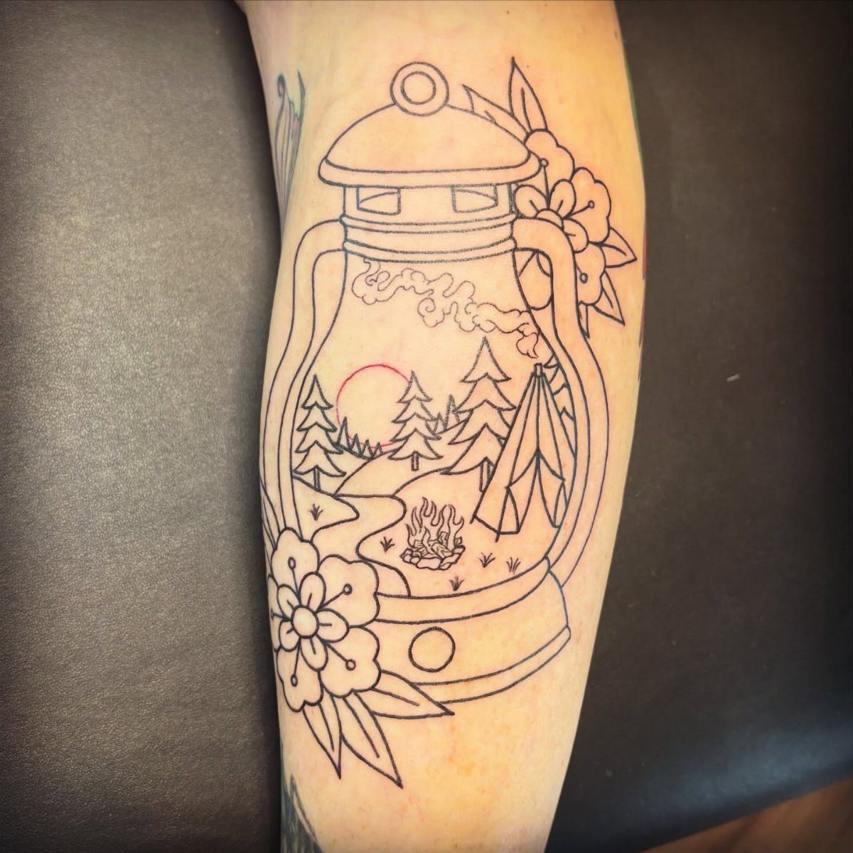 6 Tent Tattoo Ideas for Camping and Circus Styles 5 A line art tattoo of a lantern containing a camping scene with a tent and trees.