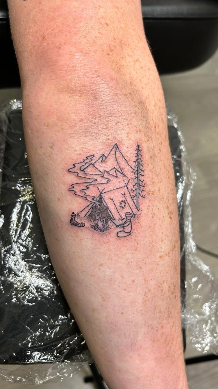 6 Tent Tattoo Ideas for Camping and Circus Styles 1 A minimalist line art tattoo of a tent, mountains, and trees on a person's leg.