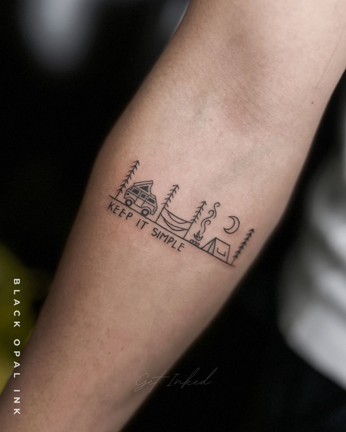 6 Tent Tattoo Ideas for Camping and Circus Styles 3 A minimalist black ink tattoo on a forearm depicting camping elements and text.