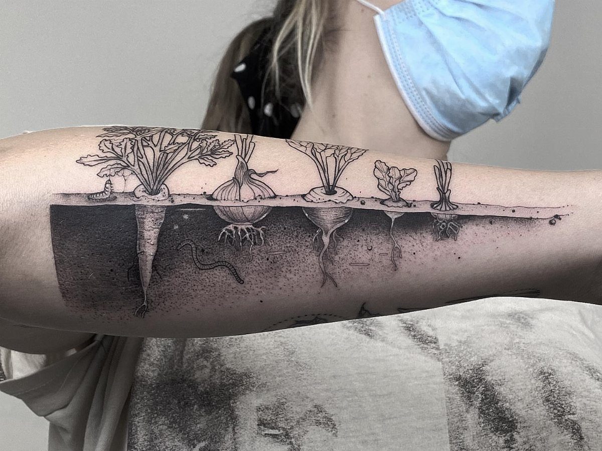 The Most Beautiful Radish Tattoo: 8 Designs for Your Next Ink 8 A detailed black and grey tattoo of various root vegetables growing in soil on an arm.