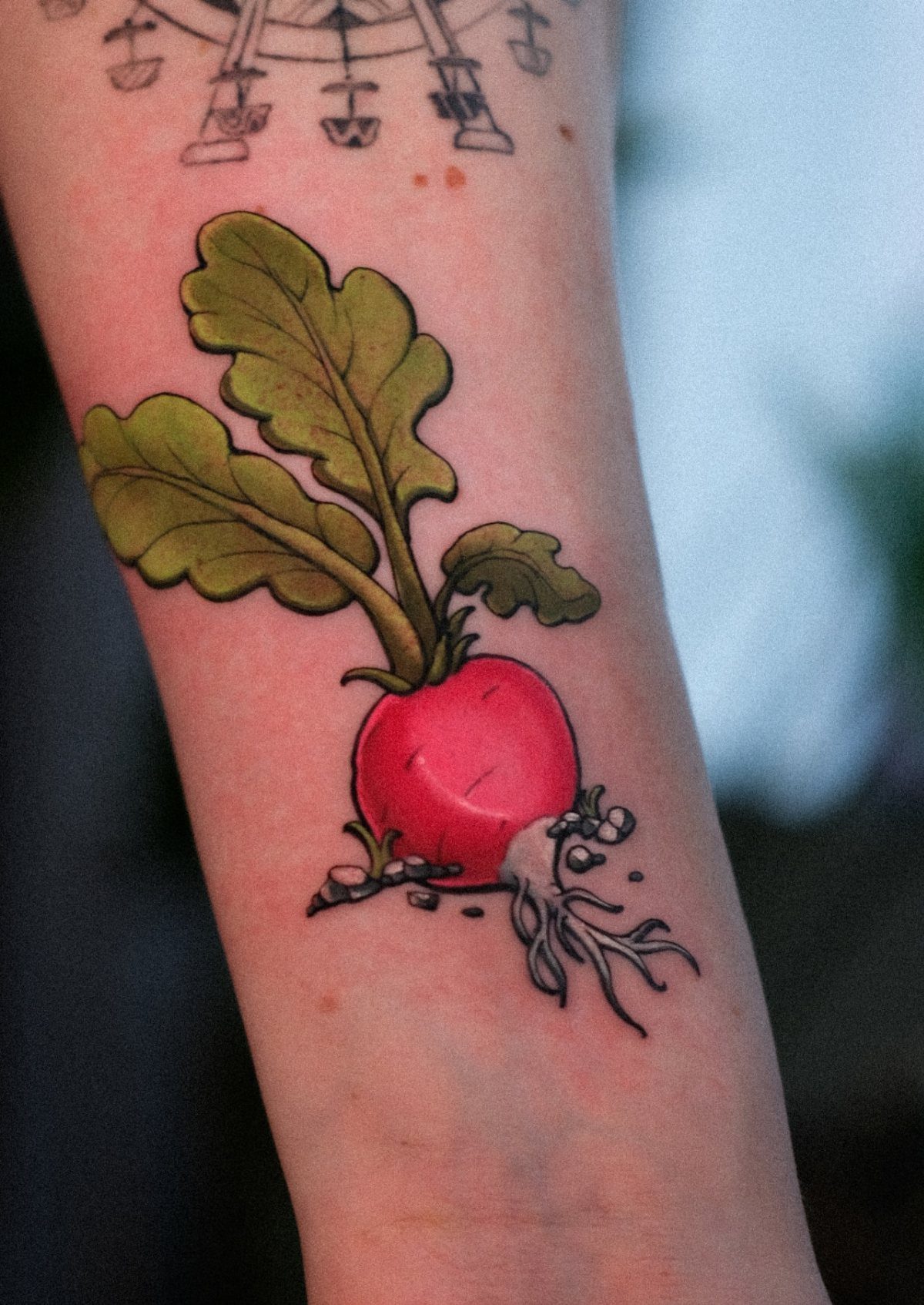 The Most Beautiful Radish Tattoo: 8 Designs for Your Next Ink 6 A vibrant red radish tattoo with green leaves and white roots on a person's arm.