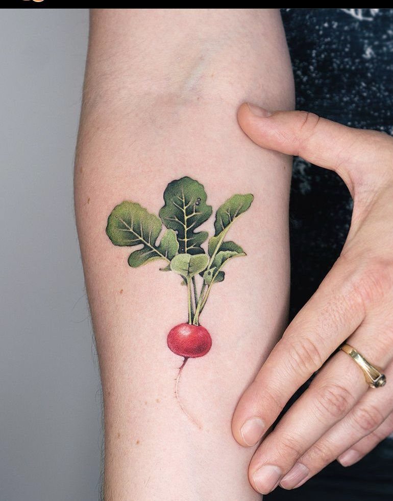 The Most Beautiful Radish Tattoo: 8 Designs for Your Next Ink 1 A detailed botanical radish tattoo with green leaves and a red bulb on a person's forearm.