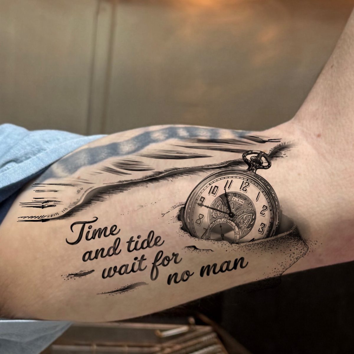 Time Waits for No Man Tattoo: 6 Designs That Mark the Moment 2 A black and grey tattoo of a pocket watch and ocean waves with cursive text on an arm.