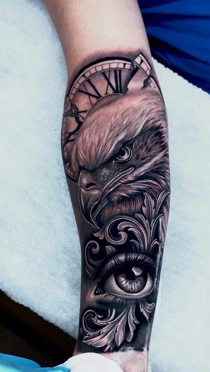 Time Waits for No Man Tattoo: 6 Designs That Mark the Moment 1 An eagle and eye tattoo with a Roman numeral clock face on a person's arm.