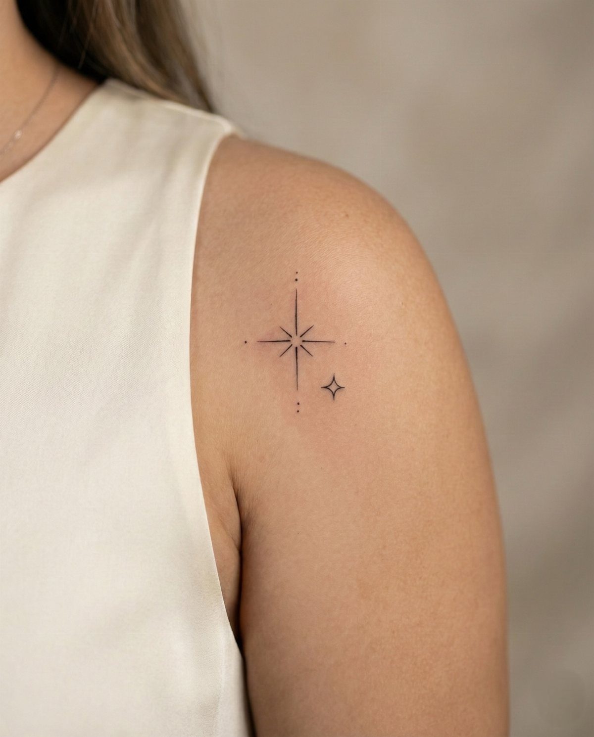 6 Twinkle Star Tattoo Ideas for Light, Sparkly Ink 3 A small fine-line star tattoo with decorative dots on a person's shoulder.
