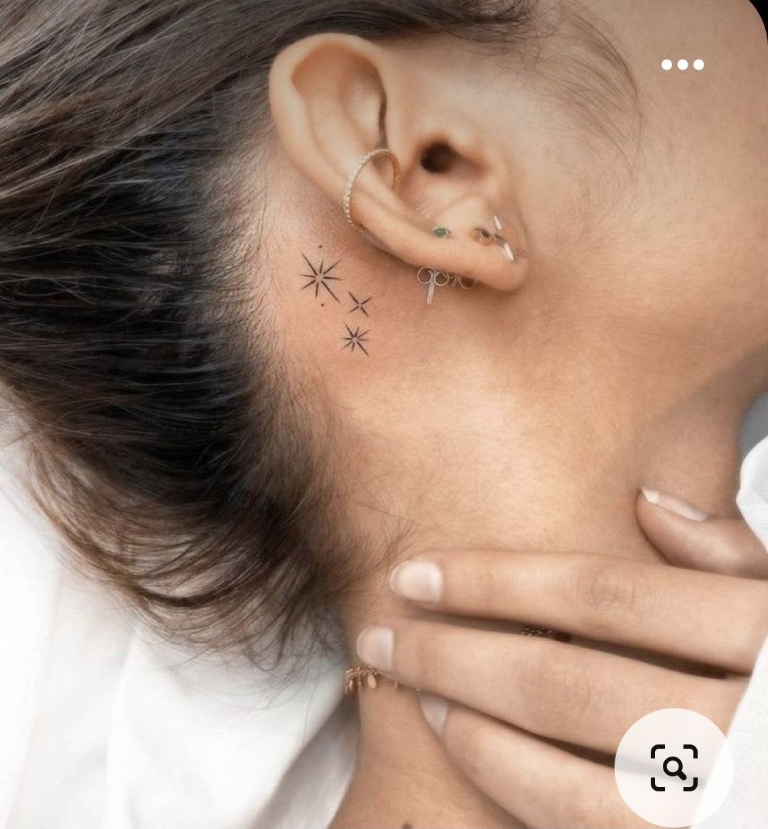 6 Twinkle Star Tattoo Ideas for Light, Sparkly Ink 5 Small black fine-line starburst tattoos located on the skin just behind a person's ear.