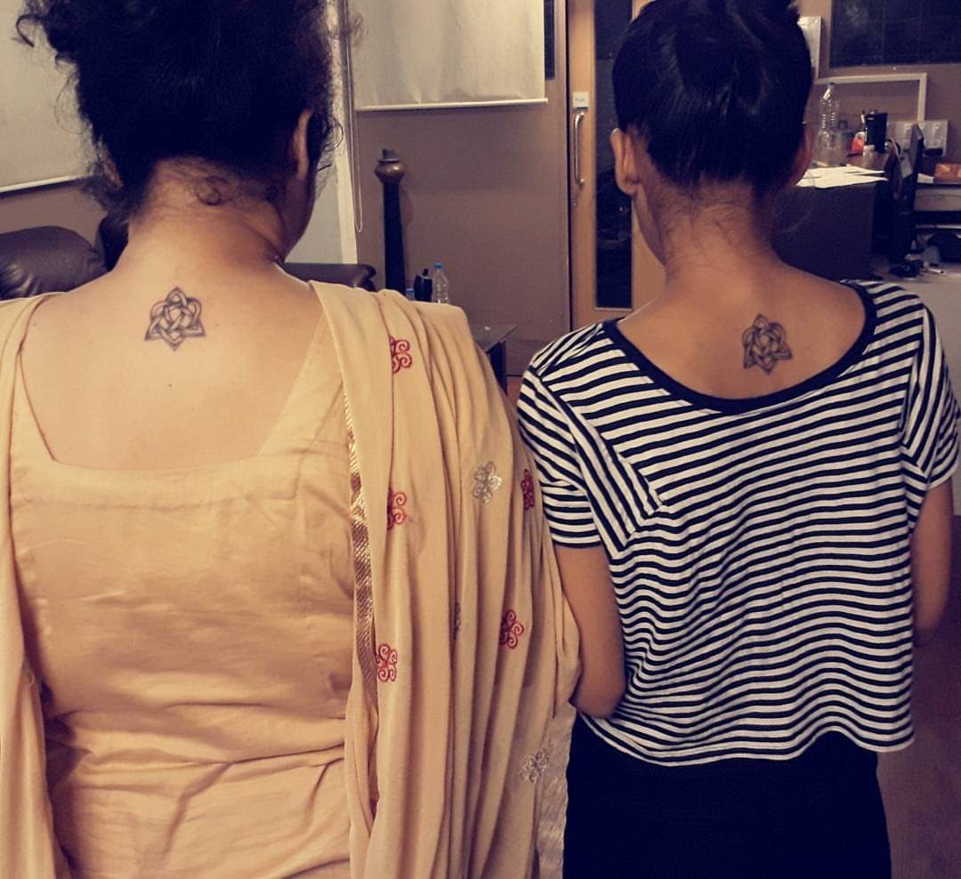 7 Unconditional Love Tattoo Ideas for Quiet, Lasting Ink 4 Two women showing small Celtic knot tattoos on their upper backs while facing away.