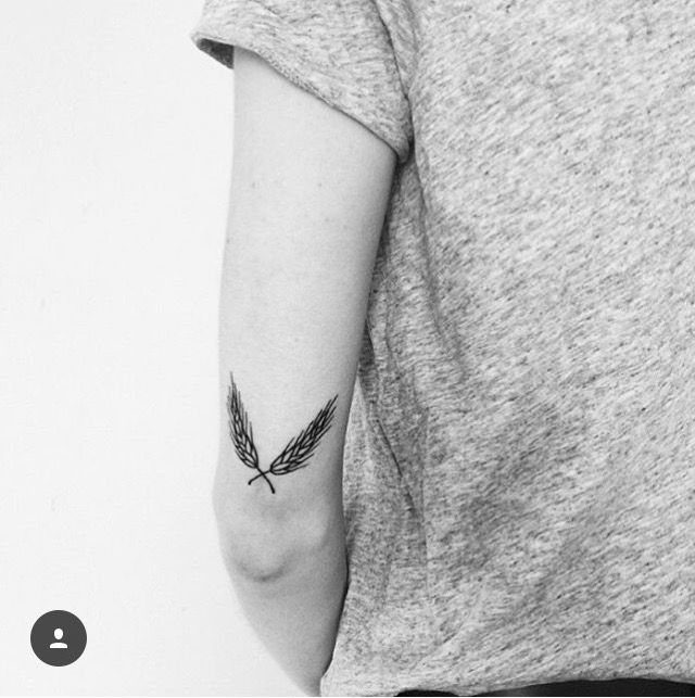 6 Wheat Tattoo Ideas for Your Next Ink 5 A black ink tattoo of two crossed wheat stalks on a person's arm.