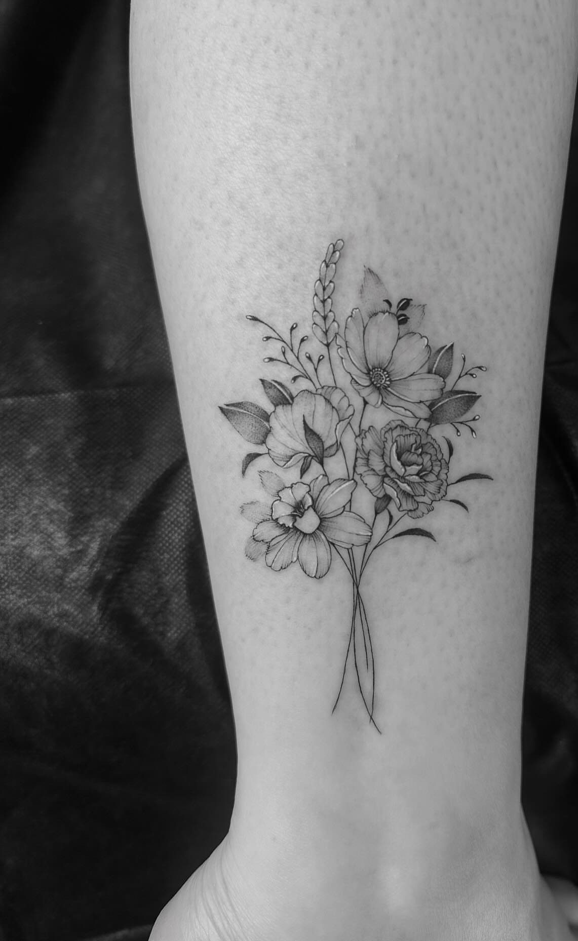 6 Wheat Tattoo Ideas for Your Next Ink 2 A fine line black and grey tattoo of a floral bouquet with wheat on a leg.