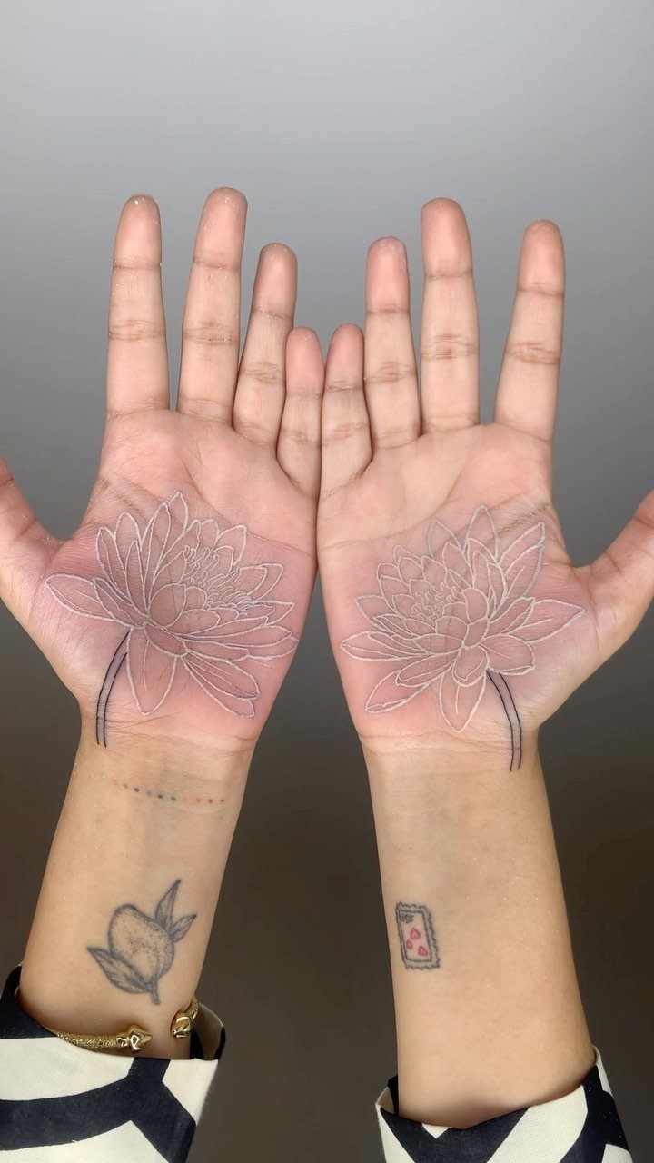 White Ink Water Lily Tattoo: 7 Ideas for Subtle Floral Ink 7 Two palms displaying delicate white ink water lily tattoos with fine line details.